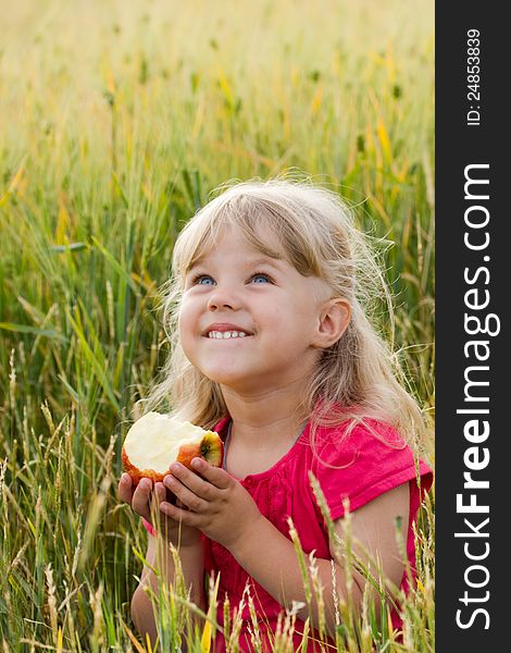 Beautiful blue-eyed girl biting an apple in a wheat field. Beautiful blue-eyed girl biting an apple in a wheat field