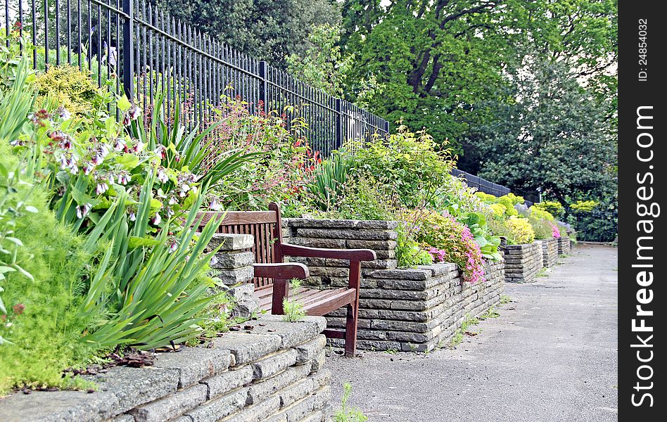 Photo of a tranquil path with bench and raised stone flower borders. Photo of a tranquil path with bench and raised stone flower borders.