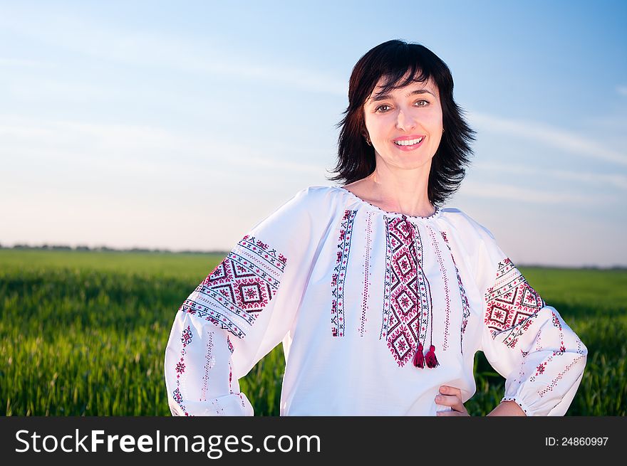 Smiling ukrainian woman outdoors on field in traditional shirt