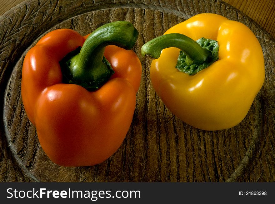 Two sweet peppers on a wooden board.