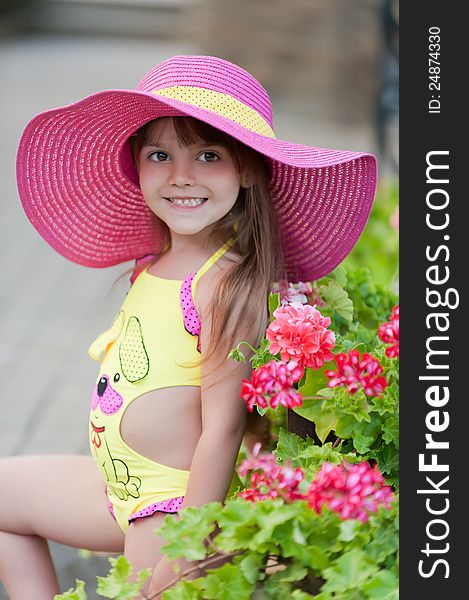 Little girl in hat posing with beautiful flowerbeds. Little girl in hat posing with beautiful flowerbeds