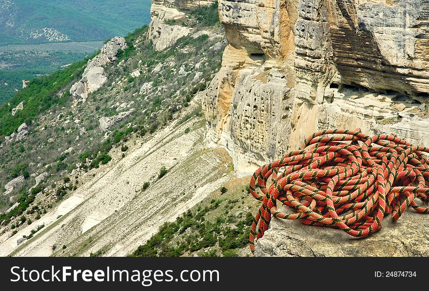 Climbing rope coiled up on the peak of the mount. Mountain climber ropes on the high rock. Adventure equipment - alpine rope at the edge of cliff. Climbing rope coiled up on the peak of the mount. Mountain climber ropes on the high rock. Adventure equipment - alpine rope at the edge of cliff.