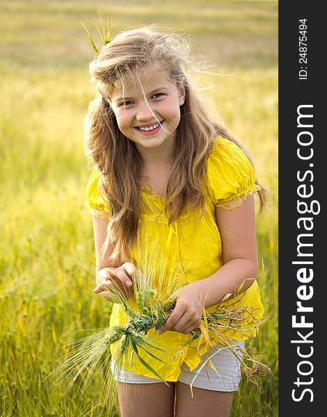 Cute girl on the weat meadow in summer day weaves a wreath. Cute girl on the weat meadow in summer day weaves a wreath