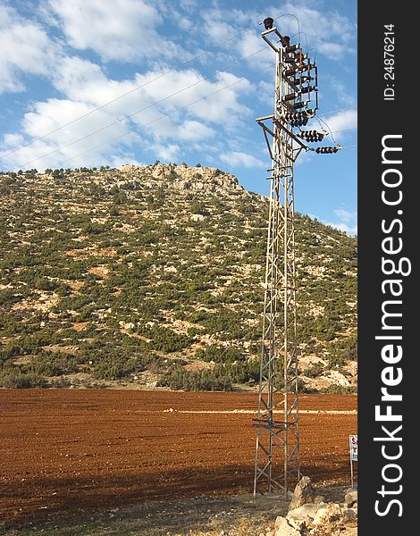 Field an mountain with a elektric power mast in front. Field an mountain with a elektric power mast in front