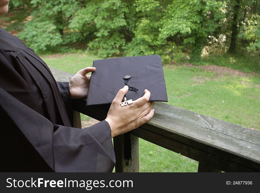 A young graduate holding her cap and staring off into the distance. Area left at right for writing, etc. A young graduate holding her cap and staring off into the distance. Area left at right for writing, etc.