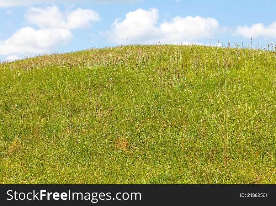 Green grass hill against a blue summer sky. Green grass hill against a blue summer sky