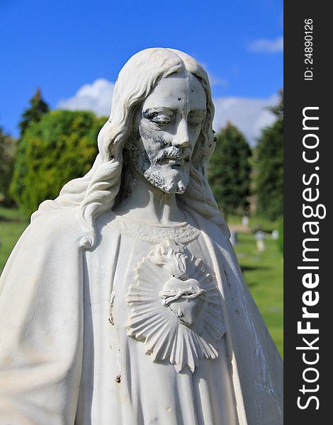 Image of a statue of Jesus Christ in a cemetery, with trees in the background. Image of a statue of Jesus Christ in a cemetery, with trees in the background