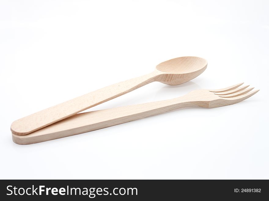 The spoon and the fork from the yellow wood on the white background. The spoon and the fork from the yellow wood on the white background