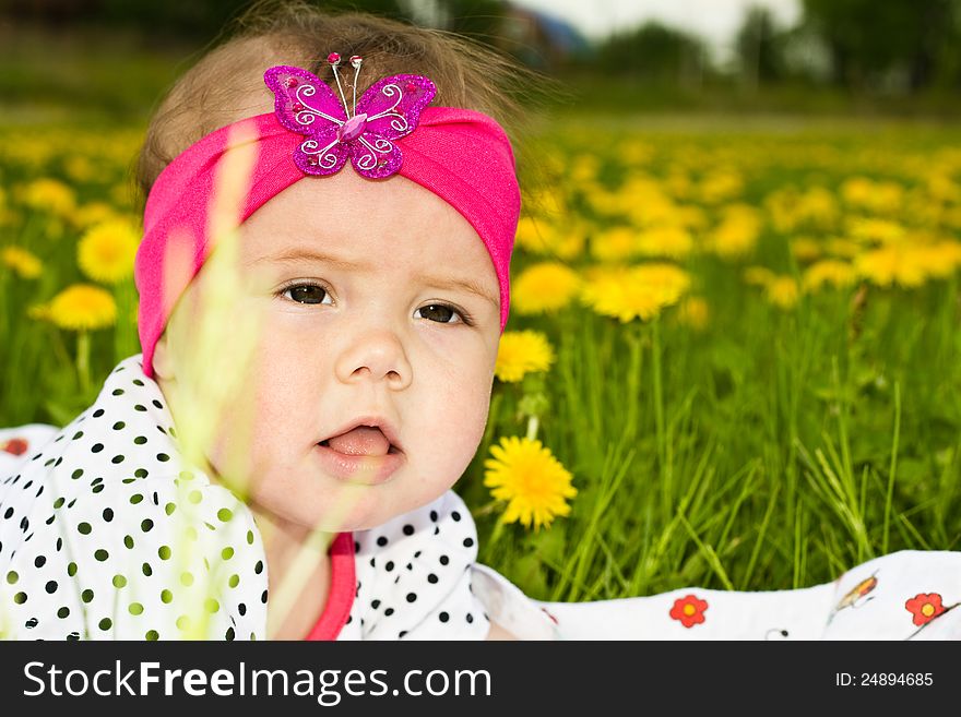 Portrait of a baby girl in the green grass in the summer outdoors