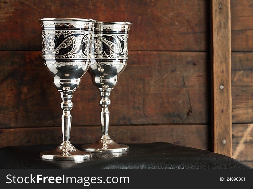 Pair of nice vintage silver goblets on old wooden background