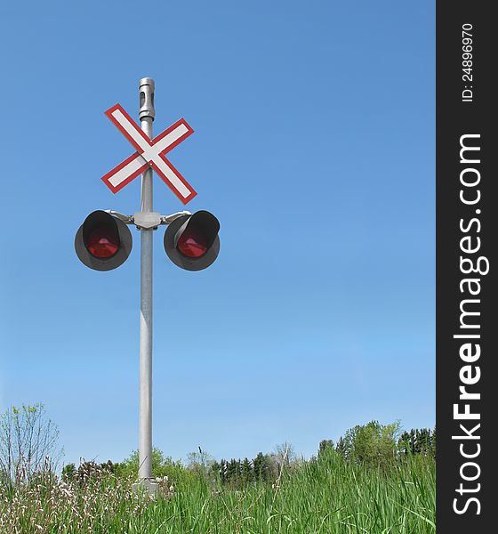 Railroad crossing signal in a rural area against a blue sky. Room on side for copy or text. Railroad crossing signal in a rural area against a blue sky. Room on side for copy or text.