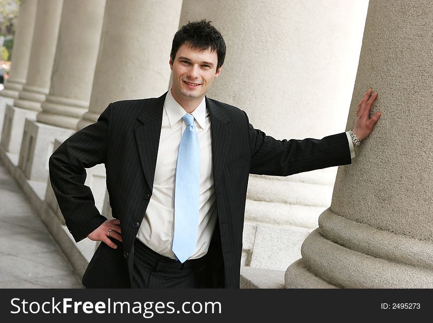 Young businessman leaning on a pillar. Young businessman leaning on a pillar.