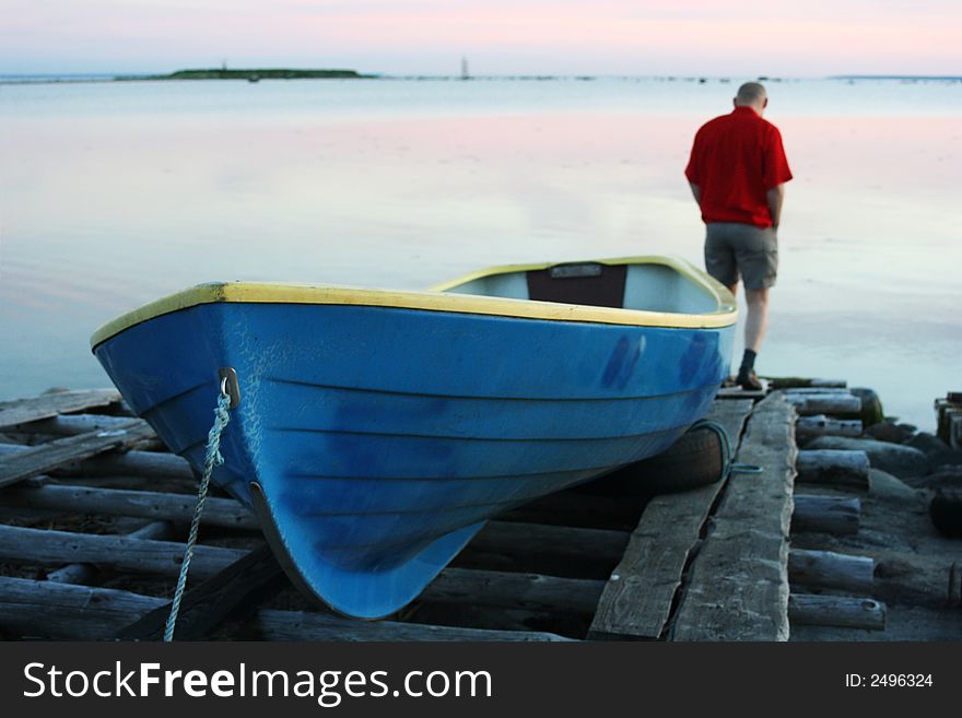 Lonely man and boat on the seacoast. Lonely man and boat on the seacoast