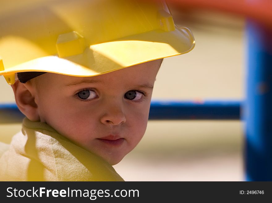 Young child with beautiful blue eyes wearing a yellow hard hat. Young child with beautiful blue eyes wearing a yellow hard hat