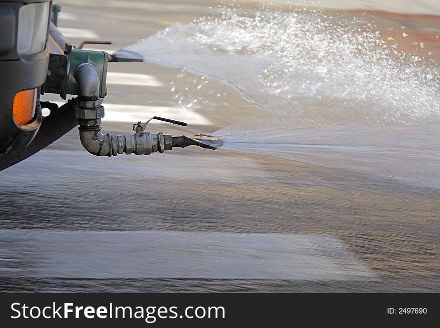 Panning and close-up image of a steam cleaning car in action in a city street.Complex motion blur effect produced by the water steam movement and the pavement movement below the water.The front car detail is in very good focus for a subject in motion. Panning and close-up image of a steam cleaning car in action in a city street.Complex motion blur effect produced by the water steam movement and the pavement movement below the water.The front car detail is in very good focus for a subject in motion.