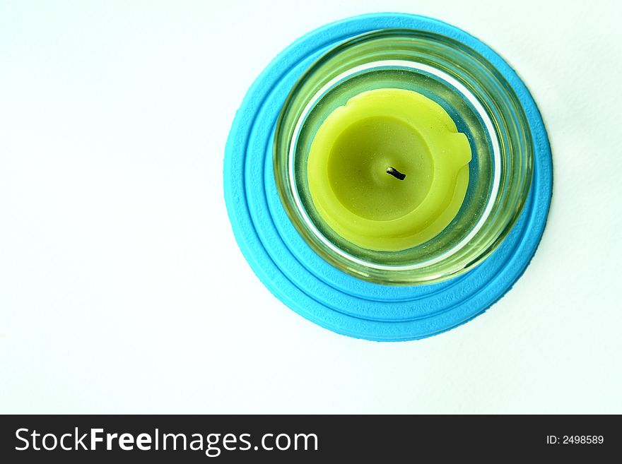 Lime colored candle in a glass holder on a blue foam coaster. Lime colored candle in a glass holder on a blue foam coaster