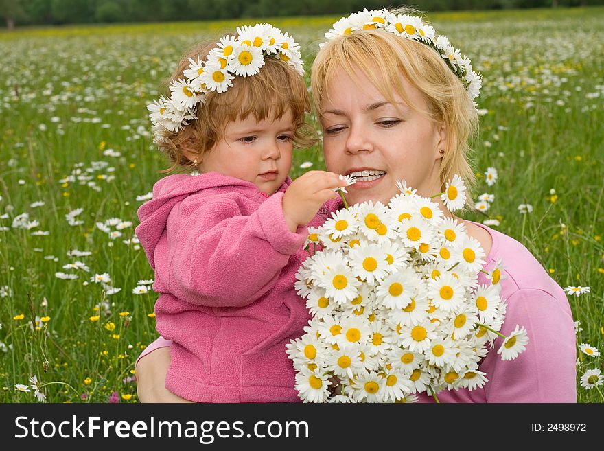 Woman and her baby girl looking at a beautiful daisy bouquet they just picked from the meadow. Woman and her baby girl looking at a beautiful daisy bouquet they just picked from the meadow