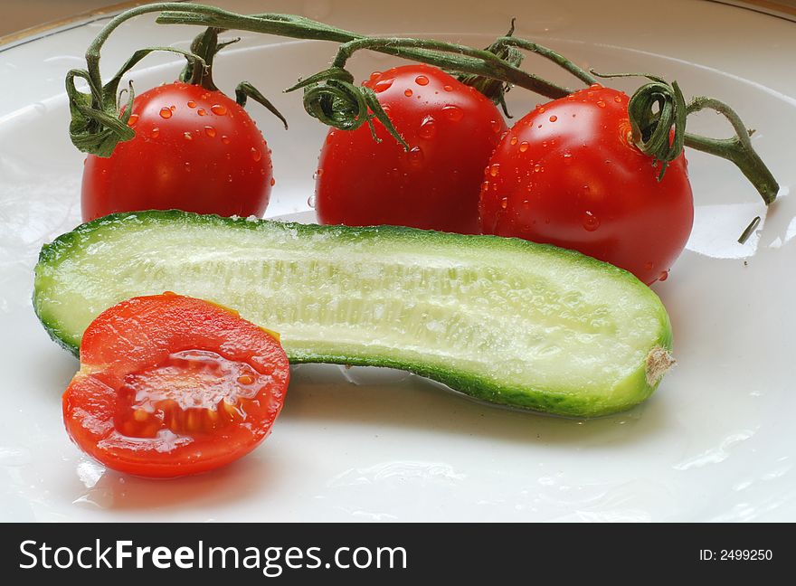Tomatoes with water drops on them and cucumber slice. Tomatoes with water drops on them and cucumber slice