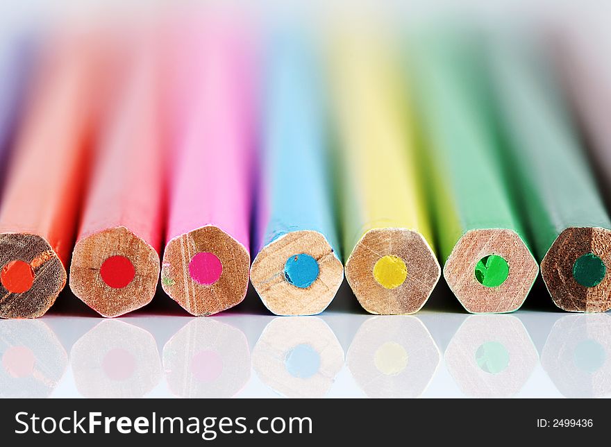 A row of color pencil ends with reflection. Shallow DOF with only ends sharp.