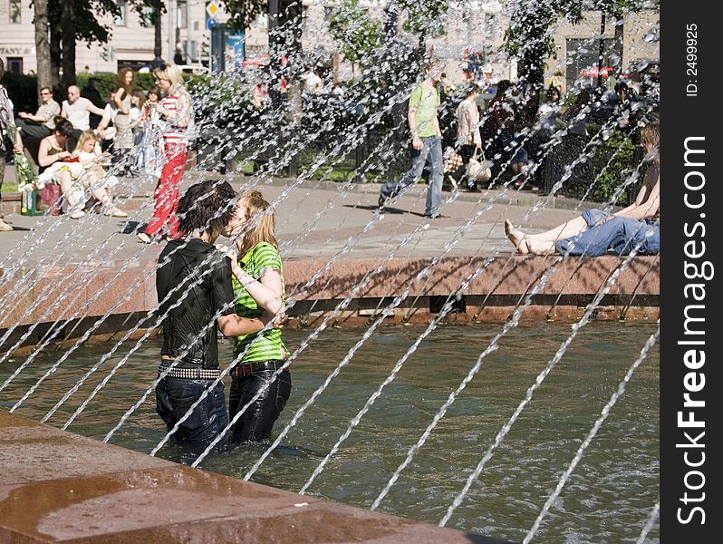 A boy and a girl are kissing standing in a fountain. A boy and a girl are kissing standing in a fountain