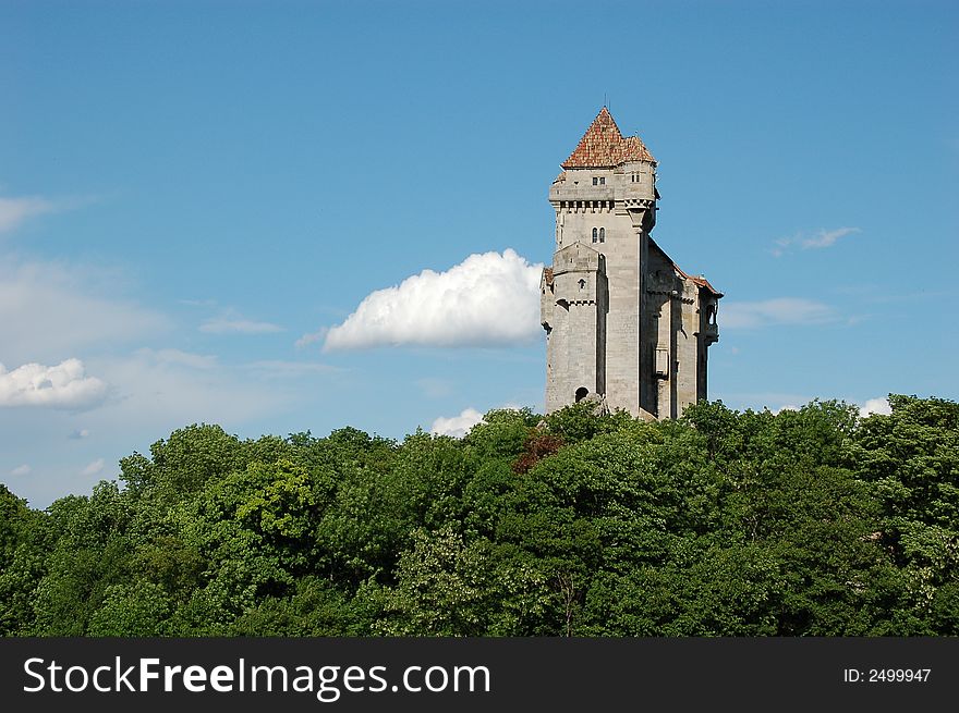 Castle with high tower above green forrest with blue sky with white cloudes. Castle with high tower above green forrest with blue sky with white cloudes