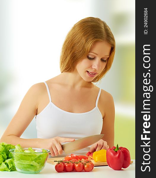 Beautiful young woman, a housewife preparing dinner vegetable salad in the kitchen at home
