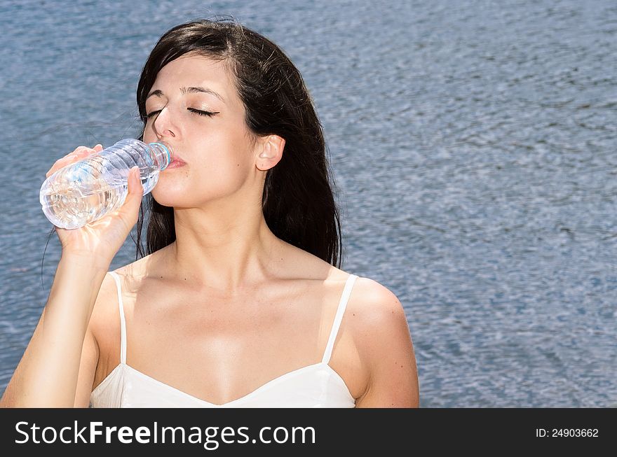 Woman drinking water to quench the thirst on a hot summer day. Woman drinking water to quench the thirst on a hot summer day.