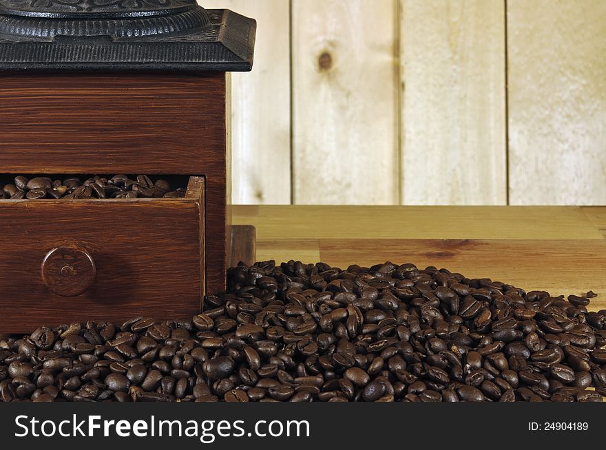 Old coffee grinder and whole coffee beans on wood background