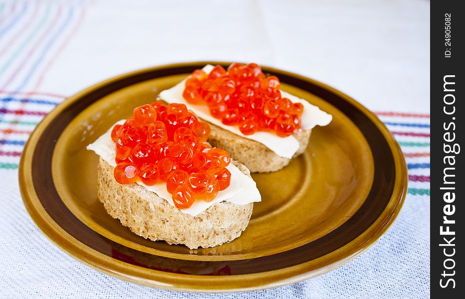 Red caviar sandwich on small ceramic plate