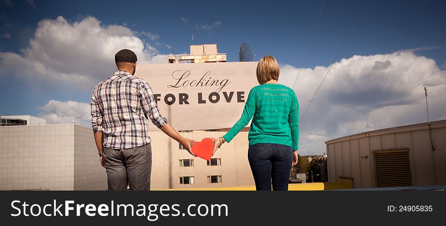 Engaged couple in front of looking for love sign. Engaged couple in front of looking for love sign