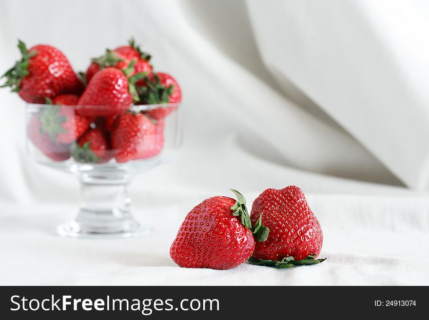 Transparent glass vase full of red strawberries on white textile background with free space for text. Transparent glass vase full of red strawberries on white textile background with free space for text