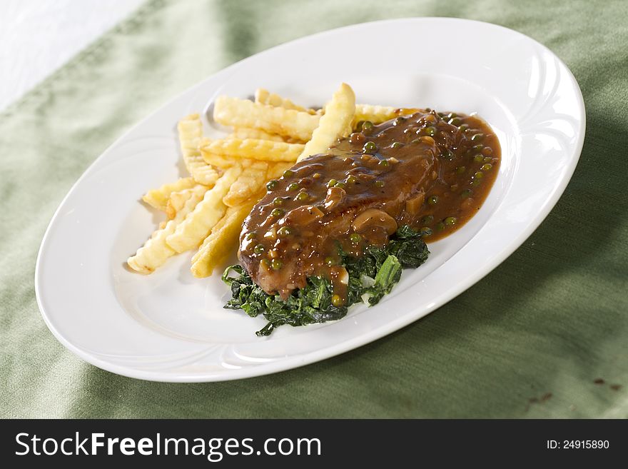Beef steak with brown sauce spinach and french fries. Beef steak with brown sauce spinach and french fries