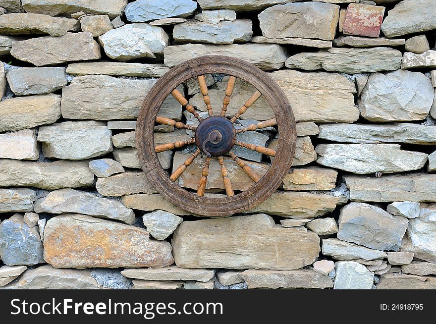 Vintage spinning wheel against stone wall background. Vintage spinning wheel against stone wall background