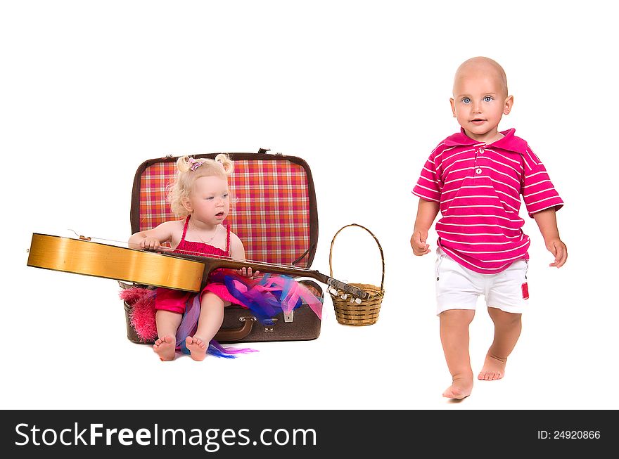 Boy and girl playing near a suitcase, a guitar, on white background