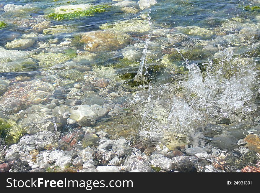 A rock falling into the water making a splash. A rock falling into the water making a splash