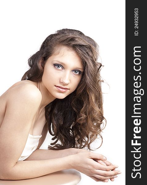 Beautiful young woman in white dress with curly hair, looking on camera, over white background. Beautiful young woman in white dress with curly hair, looking on camera, over white background
