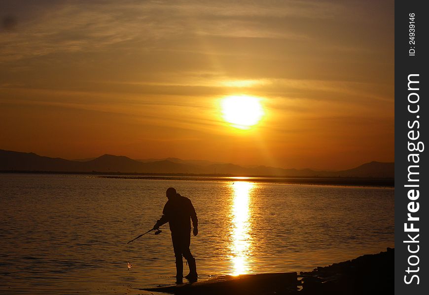 Man fishing on the sunset beach. Man fishing on the sunset beach