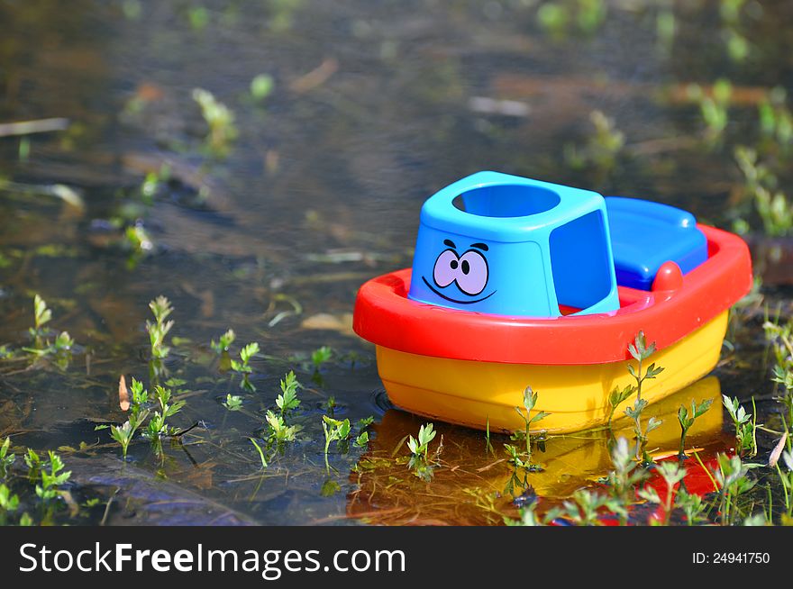 The small toy ship floats in the real water. The small toy ship floats in the real water