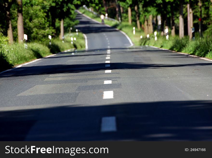 A road in summer wide with a bicyclist riding up a hill far away in the distance. A road in summer wide with a bicyclist riding up a hill far away in the distance