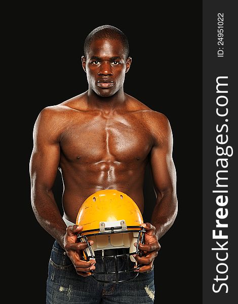 Young African American Man holding a Football Helmet isolated on a dark background