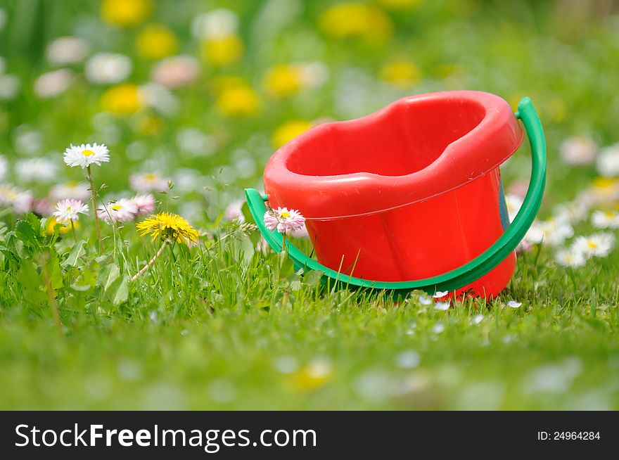 A kidsâ€™ sand bucket on the grass in the garden. A kidsâ€™ sand bucket on the grass in the garden