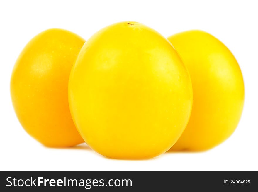 A close-up of three yellow cherry plums on a white background. A close-up of three yellow cherry plums on a white background