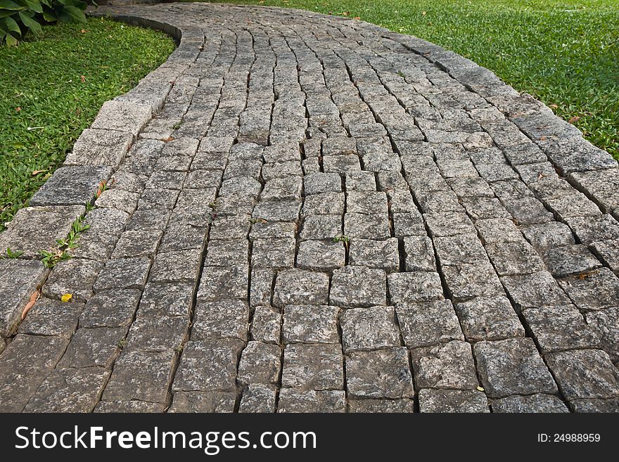 The Stone block walk path in the park with green grass background