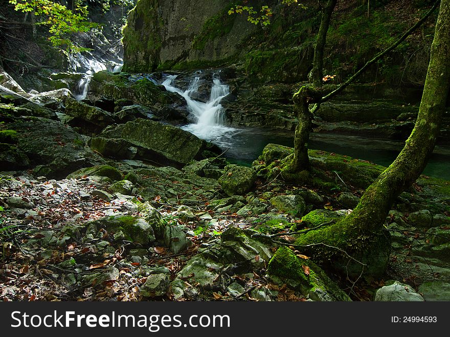 Rough river in mountains with small waterfall