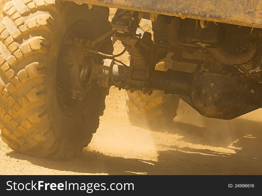 Detailed view of the wheels, tires and truck shaft that goes in the dust of the desert. The rays of light shine through the wheels. Detailed view of the wheels, tires and truck shaft that goes in the dust of the desert. The rays of light shine through the wheels.