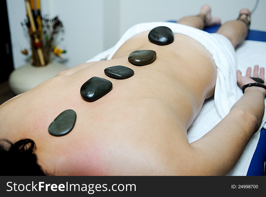 Man relaxing on massage bed with hot stones