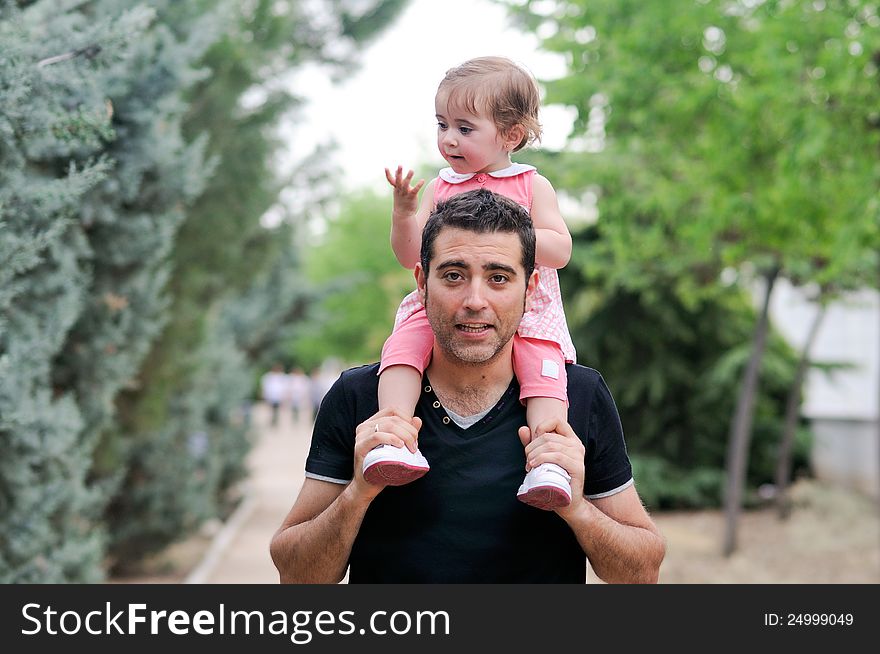 Little girl walking on the shoulders of her father in the park. Little girl walking on the shoulders of her father in the park