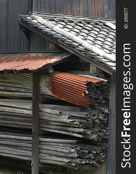 An old dilapidated Japanese shed with a rusted roof and a supply of old bamboo. An old dilapidated Japanese shed with a rusted roof and a supply of old bamboo.