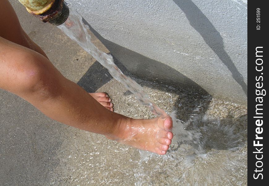 Child is rinsing her feet in cold water form teh well. Child is rinsing her feet in cold water form teh well