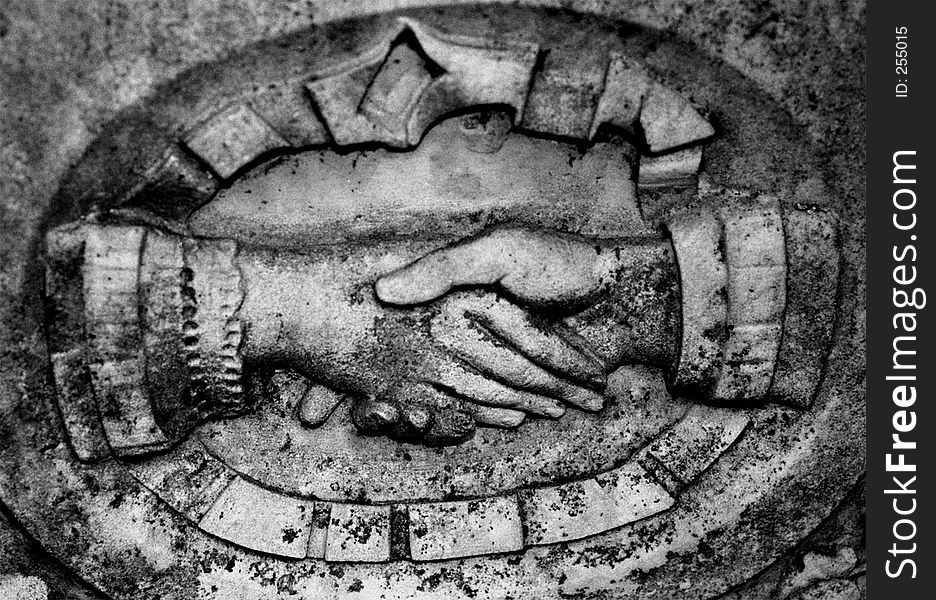 Grave stone detail of hands shaking